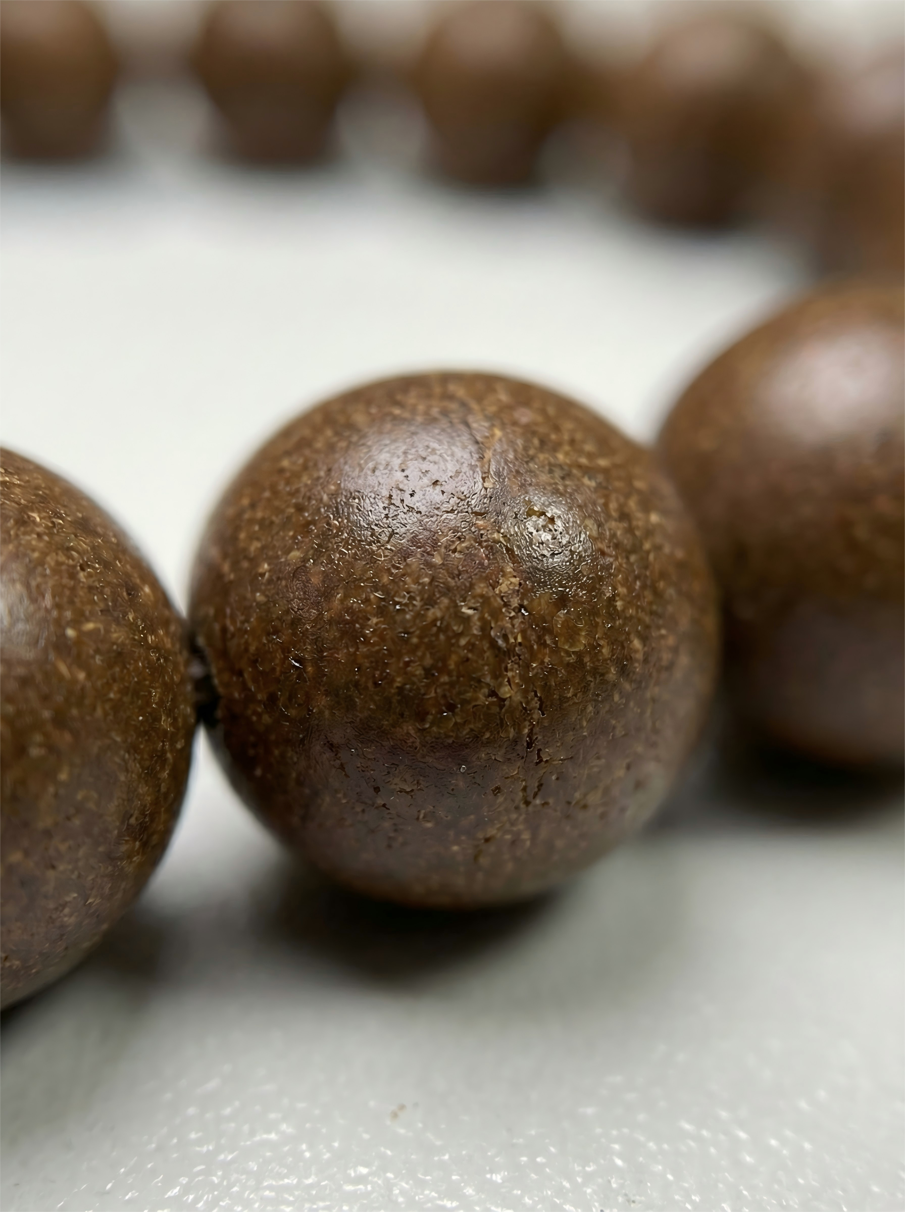 Macro close up of handmade Osmanthus herbal clay beads showing natural matte texture and organic grain without chemical glue.
