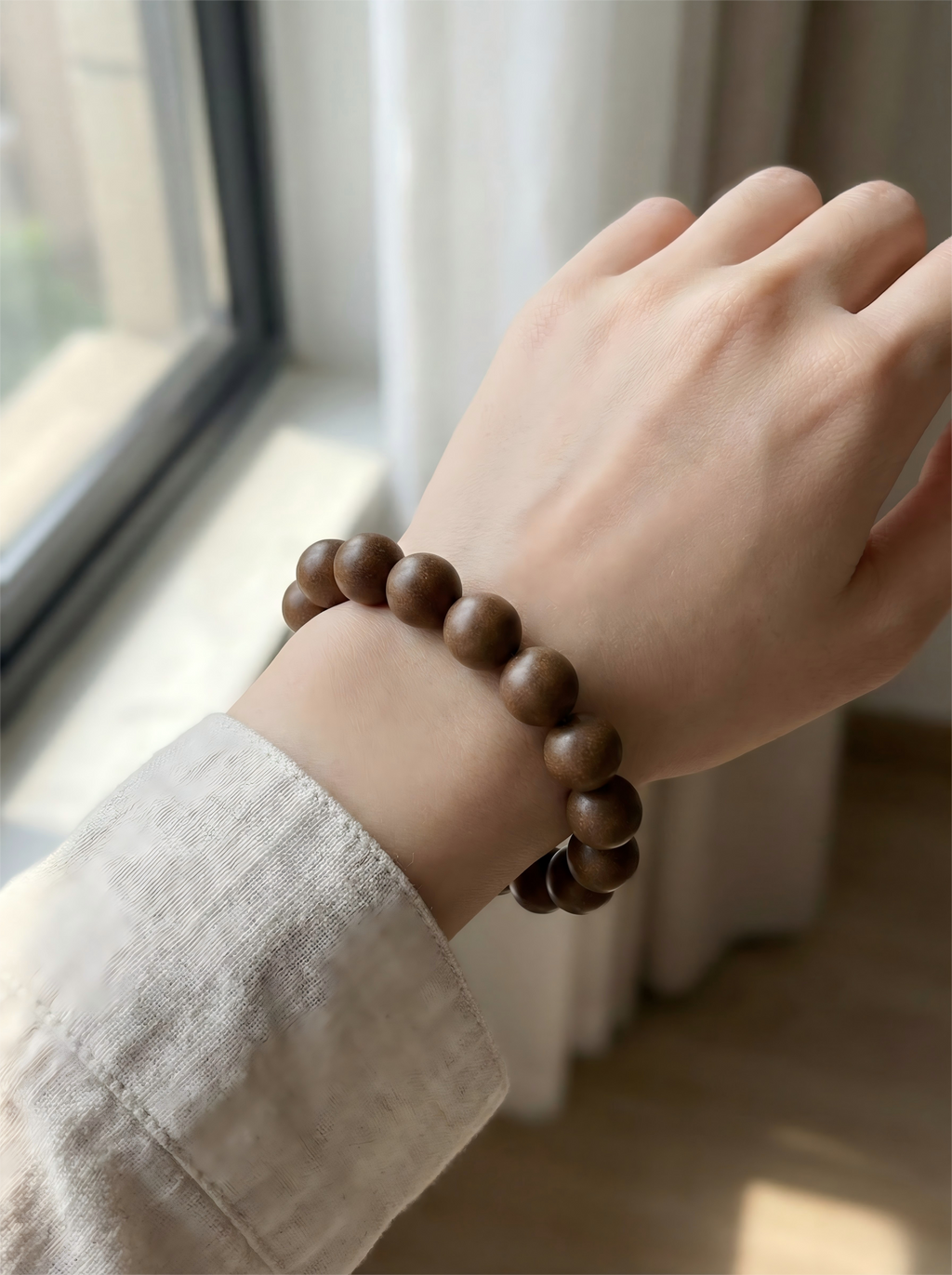 Woman wearing Osmanthus and sandalwood herbal bracelet on wrist with linen clothing for relaxation and healing style.