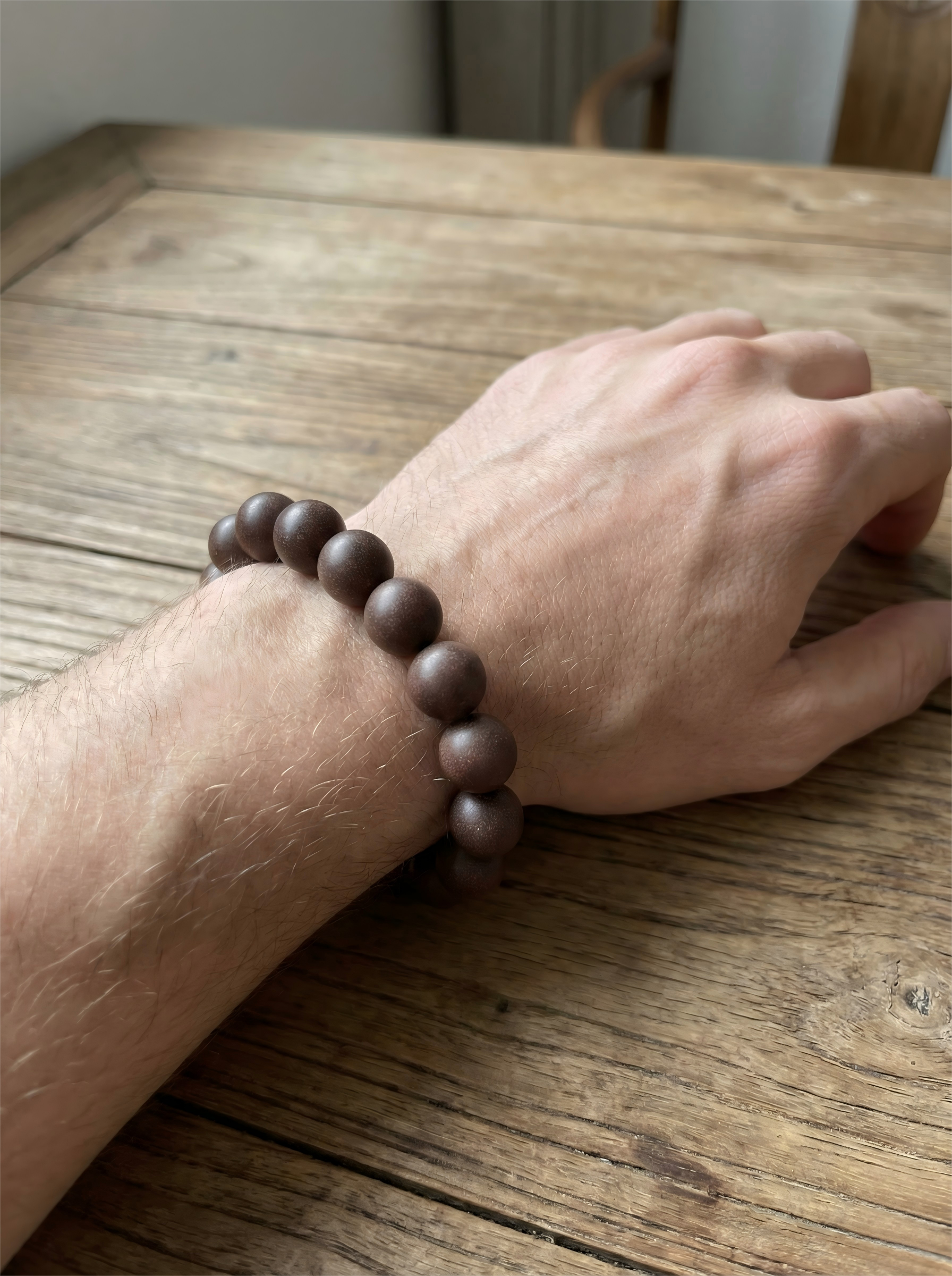 Man wearing Saffron and Nutmeg Tibetan herbal bracelet on wrist with linen shirt for meditation and yoga style.