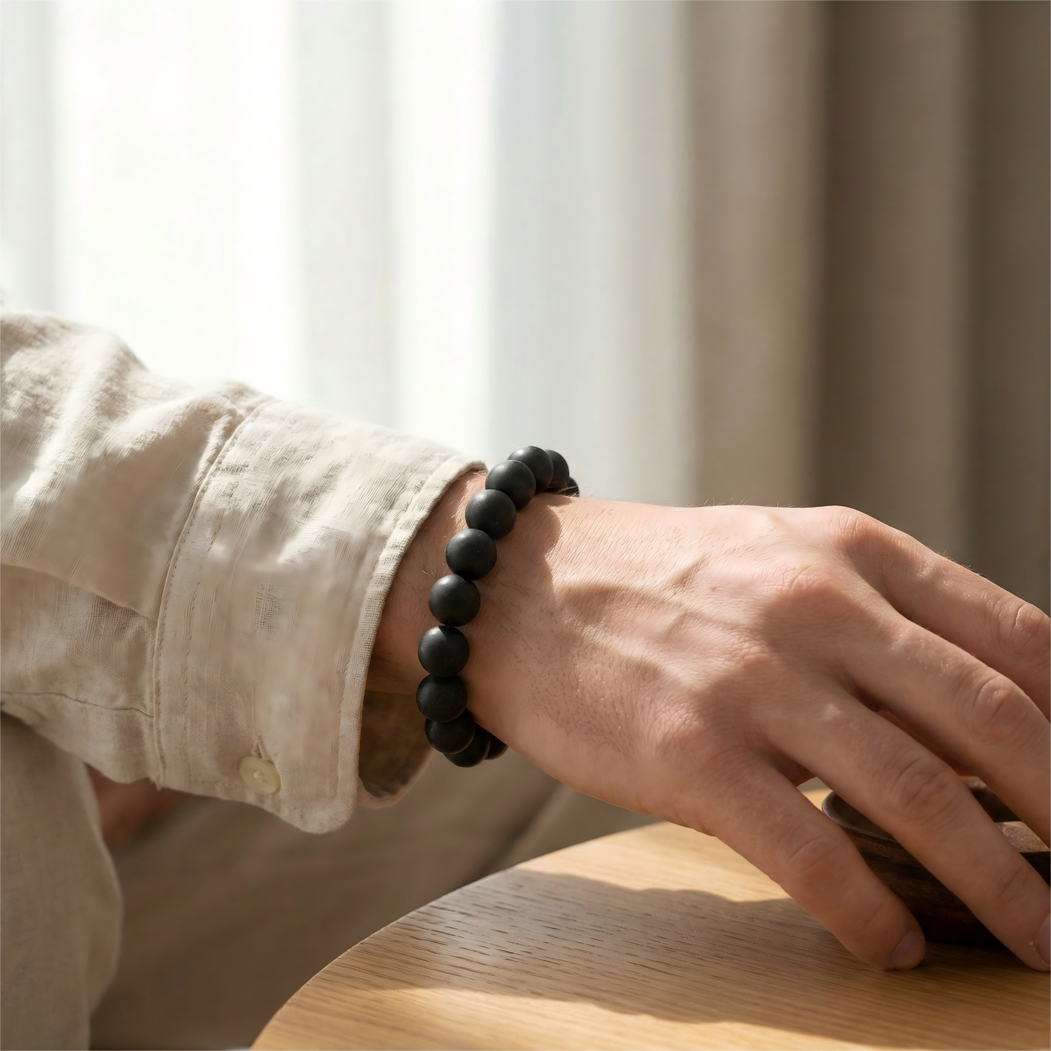 Man wearing black ambergris agarwood herbal bracelet on wrist with linen shirt for confidence and luxury style.