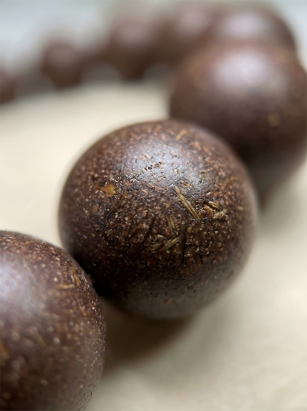 Macro close up of handmade Tibetan herbal clay beads showing Saffron and Nutmeg texture and organic grain without chemical glue.