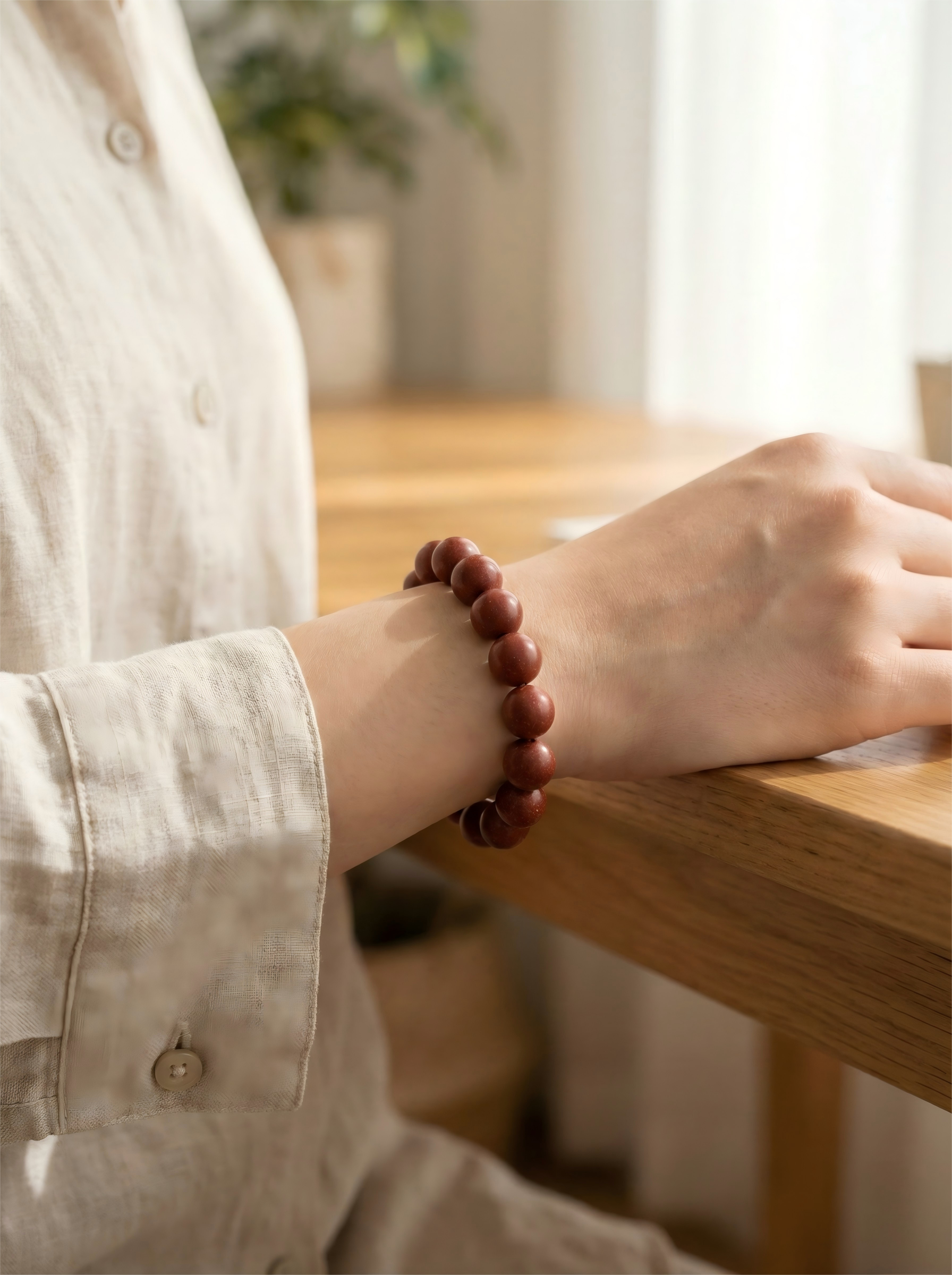 Woman wearing Crimson Letter rose and sandalwood herbal bracelet on wrist with linen clothing for self love and relaxation.